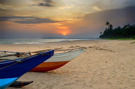 Fishing boats on the shore of the ocean. Tropical sunsetの写真素材