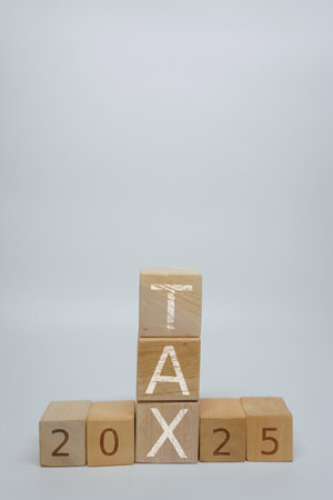 Wooden blocks arranged to spell 'Tax' on top of '2025'. Represents concepts such as finance, taxes,...
