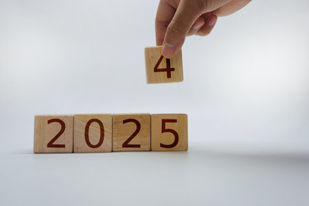 Wooden blocks displaying the years 2024 and 2025, with a hand altering the final digit, symbolizing transition or changeの写真素材