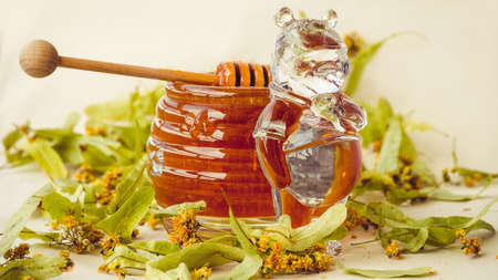Closeup of honey dipper and lime leaves, filled in crystal jar with beer.の写真素材