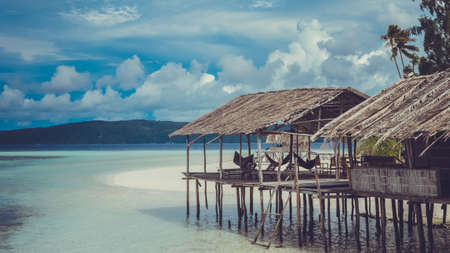 Water Hut of Homestay on Sandy Bank, Clouds in Background - Kri Island. Raja Ampat, Indonesia. West Papuaの写真素材