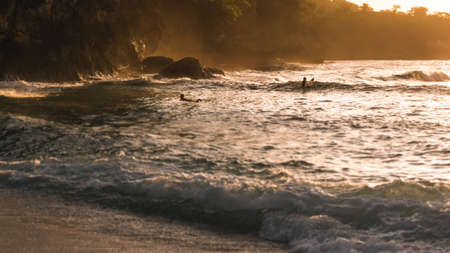 Local Kids surf on Waves in Sunset light, Beautiful Crystal Bay, Nusa Penida Baliの写真素材