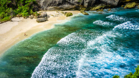 Couple on beautiful Atuh Beach with White Long Waves, Nusa Penida, Bali, Indonesiaの写真素材