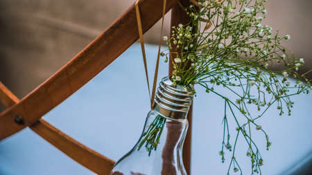 Original wedding floral decoration, mini-vases and bouquets of flowers hanging from the chair