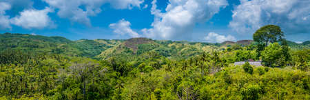 Hills covered by Jungle with Small Templein Front, Nusa Penida Island, Bali, Indonesiaの写真素材