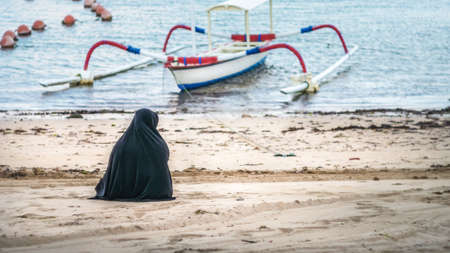 Muslim women in Abaya Niqab sitting and relaxing the beach at the sea. Nusa Dua, Baliの写真素材