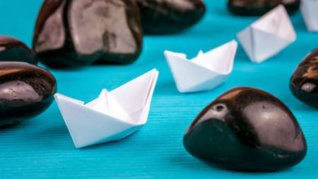 Leadership lead further white paper ships between stones on blue background. Right to left moving.
