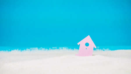 Symbol of little lilac house on the sand with bright blue backgroundの写真素材