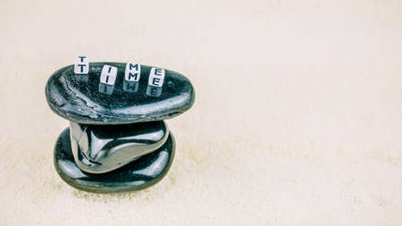 the concept of time.TIME cube letters on black stone written sand background