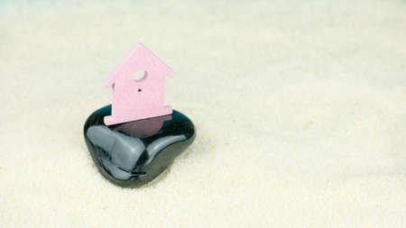 Symbol of little lilac house secured builed on black stone instead on sand