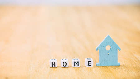 HOME horizontal word of cube letters behind blue house symbol on wooden surfaceの写真素材
