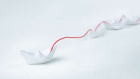 Leader ship lead further white paper ships in red towの写真素材