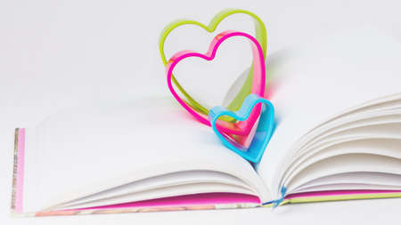Red blue and green hearts over diary book on white tableの写真素材