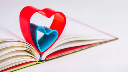 Red and blue hearts over diary book on white tableの写真素材