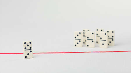 Expelled from the group, unable to cross the red line that separates them. Scene with group of domino. Concept of accusation guilty person, bulling or outcast in the team. Bright backgroundの写真素材