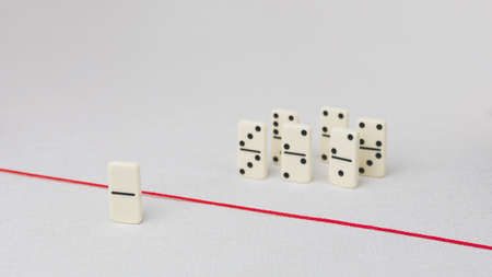 Expelled from the group, unable to cross the red line that separates them. Scene with group of domino. Concept of accusation guilty person, bulling or outcast in the team. Bright backgroundの写真素材