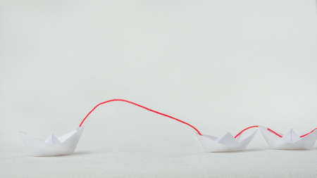 Leader ship lead further white paper ships in red towの写真素材