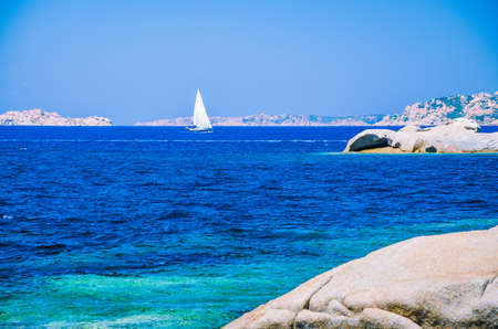 White sailboat, yacht between granite rocks in sea, amazing azure water, Sardinia, Italyの写真素材