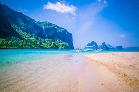 Traditional banca boat anchored at sandy beach with pure crystal clear water. El Nido, Philippinesの写真素材
