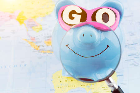 Bright smile piggy bank with sunglasses on the world ready for next travelの写真素材