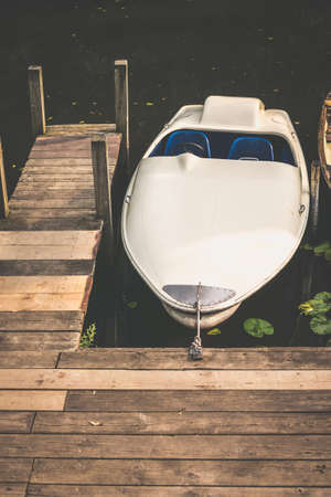 Rent Boat anchored at the wooden pier of a lake in city park. Hamburgの写真素材