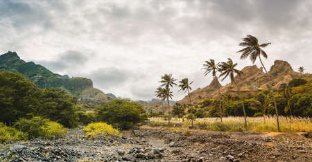 Panorama of dried-up stream surrounded by fertile green valley and rugged cliffs. Santo Antao, Cabo...