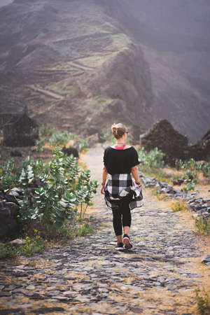 Woman hiker on the picturesque coastal cobbled route. The road joins the towns of Cruzinha,...