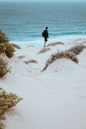 Alone traveler in snow-white dune landscape on the Atlantic coastline