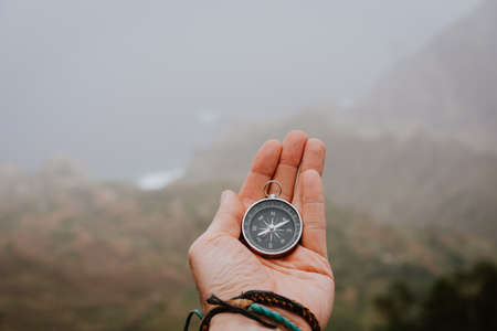 Looking at the compass to figure out right direction. Foggy valley and mountains in background. Santo Antao. Cape Cabo Verdeの写真素材