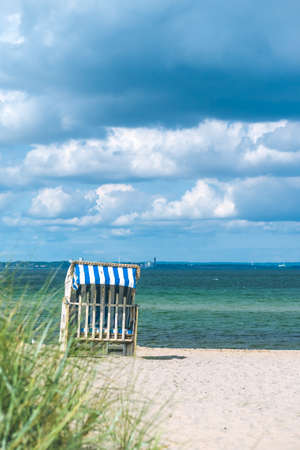 Rainy clouds above beach with blue colored roofed chairs in Travemunde. Germanyの写真素材
