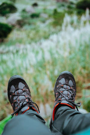 Hanging feet with trekking footwear over hill with sugarcane plants. Santo Antao Island, Cape Verdeの写真素材