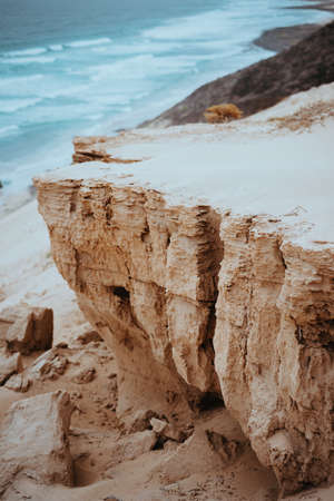 Mysterious landscape of dry sand dunes and black volcanic ground and blue ocean along coastline of Baia Das Gatas. North of Calhau, Sao Vicente Island Cape Verdeの写真素材