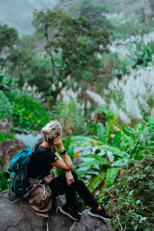 Girl resting after track on the stone and admiring spectacular green banana and sugarcane plants on the valley. Santo Antao island in Cabo Verdeの写真素材