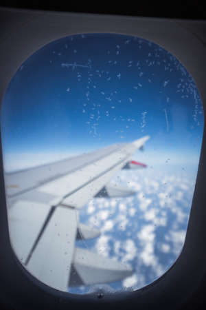 Clouds and sky as seen through window of an aircraft. Small ice crystals on the windowの写真素材