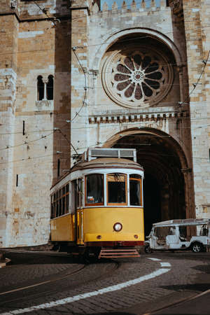 Quaint yellow tram passes directly in front of the Se Cathedral in Lisbon. Lisboa Lissabonの写真素材