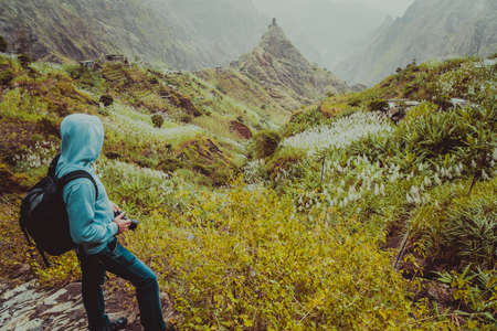 Traveler with backpack looking for motive of rural landscape with mountain peaks and ravine in dust air on the path from Xo-Xo Valley. Santo Antao Island, Cape Verdeの写真素材