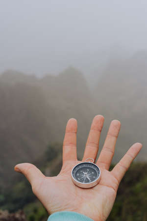 Man palm holding compass. Foggy mountainous landscapeの写真素材