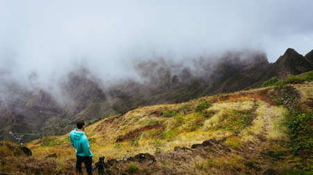 Panoramic shot of traveler taking picture of amazing steep mountain range and terrain canyon valley on the path from Xo-Xo Valley. Camera on tripod.Santo Antao Island, Cape Verdeの写真素材
