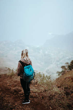 Female hiker looking down over a vertiginous misty ridge on the route to Coculi. Santo Antao Cape Verdeの写真素材