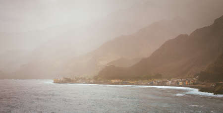Bluff volcanic coastline covered by sunlight penetrates dust. Silhouette of mountain ridges. Road to Paul Pombas, Santo Antao Cape Verdeの写真素材