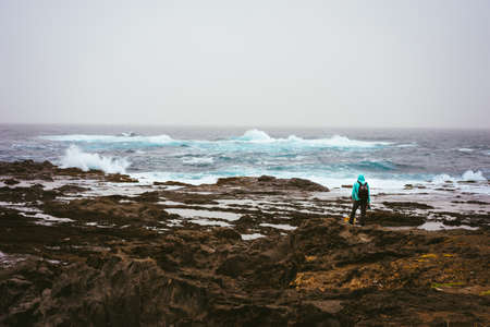 Photograph with a dog looking for motive. Waves hitting volcanic rocky coastline. Sahara dust in the sky. Santo Antao Island, Cape Verdeの写真素材