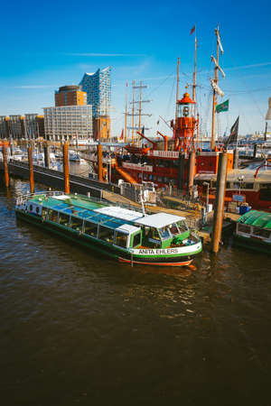 Hamburg, Germany - May 17, 2018: HafenCity, Speicherstadt: Panoramic view of Red fire patrol boat with a restaurant on the board. The modern Elbphilharmonie building in the backgroundのeditorial素材