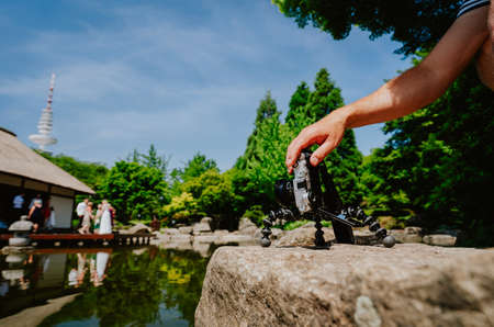 Photograph male hand handling an old vintage camera on tripod in front of water pond film wedding...