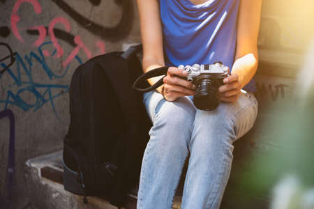 Young woman holding camera in hand sitting on stairsの写真素材