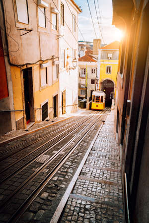 Lisbons Gloria yellow funicular in sunset beam light. Lisbon, Portugal. West side of the Avenida da Liberdade connects downtown with Bairro Alto.の写真素材