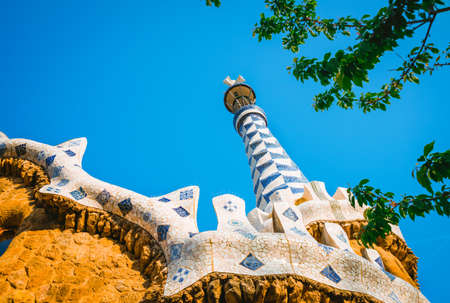 Mosaic tower and colorful roof decorations of Gingerbread House of Gaudi in Park Guell, Barcelona,...