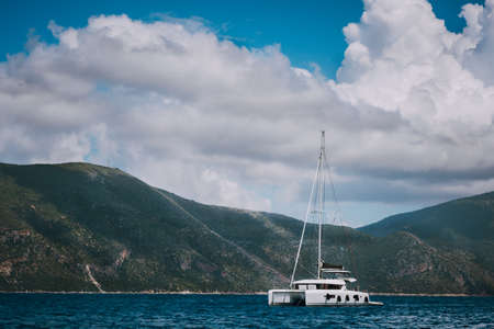 Catamaran ship in open sea near Fiskardo. Big clouds moving over the mountain shape of Ithaki...