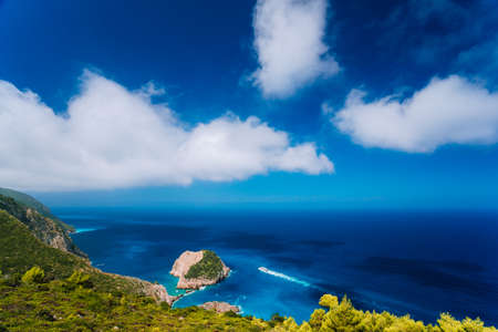 Zakynthos west fantastic coastal view. Lonely white cliff rock in sea. White tourist ship sailing full speed on open azure sea water under beautiful cloudscapeの写真素材