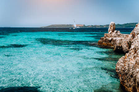 Beautiful turquoise cozy bay surrounded by white cliffs. White yacht afar in the deep blue water. Ionian islands of Greeceの写真素材