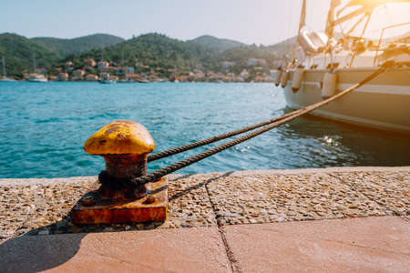 Beautiful yacht tied on the pier. Summertime feeling sunbeams, morning sunlight. Vacation on greek islandsの写真素材
